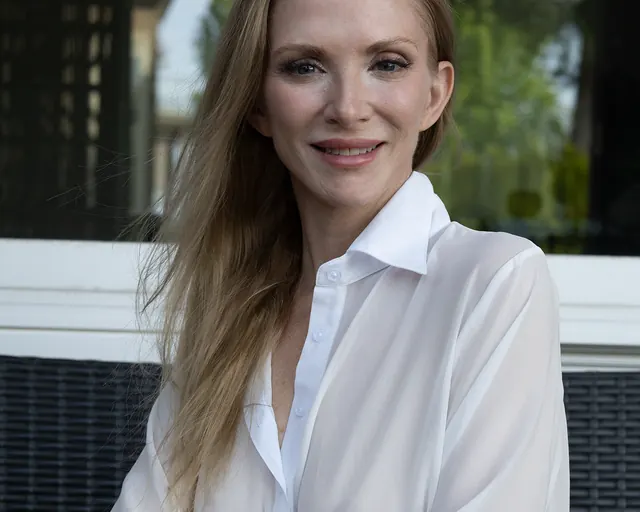 Avery smiling outdoors in a soft white blouse